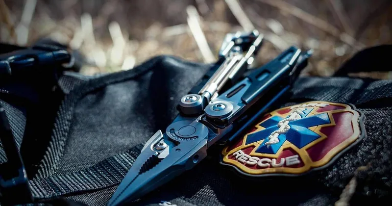 Couteaux papillon et de poche fermés disposés sur équipement tactique noir